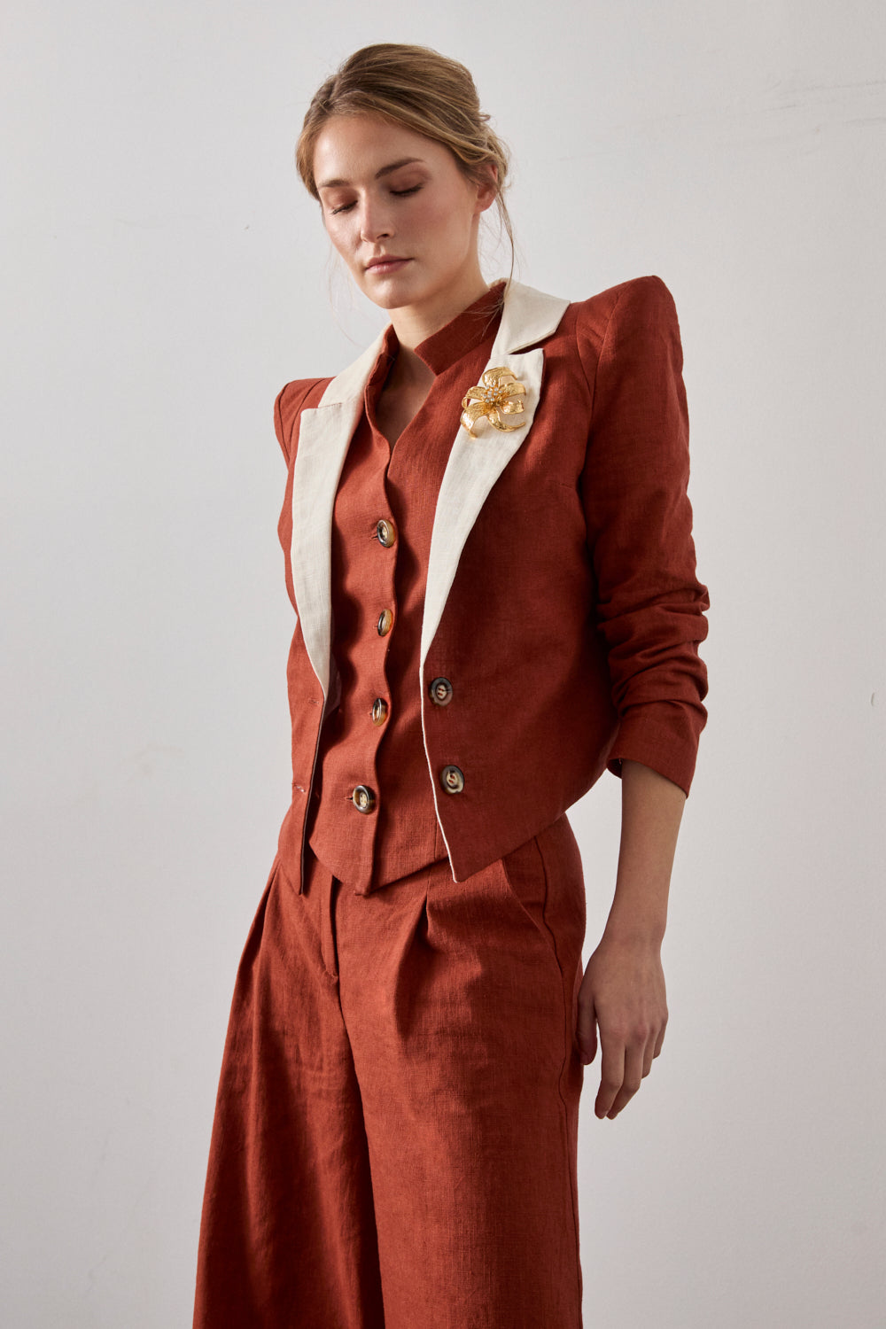 Chaqueta con hombreras en color caldera y solapa a contraste en color crema. Está forrada y se cierra con dos botones en el delantero.