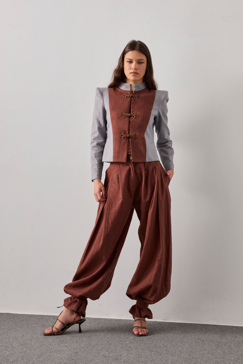 Chaqueta bicolor con cuello mao y hombreras en color gris. Detalle de chaleco a contraste en color marrón. 