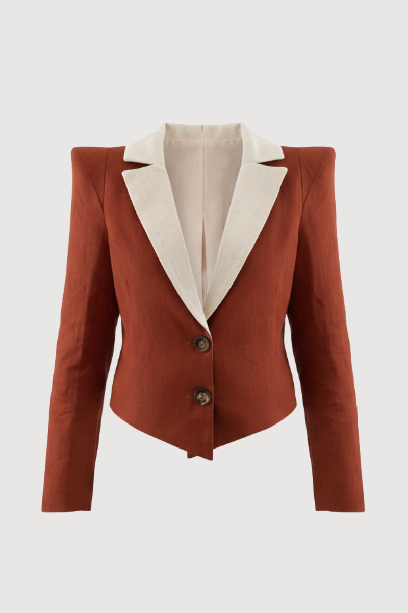 Chaqueta con hombreras en color caldera y solapa a contraste en color crema. Está forrada y se cierra con dos botones en el delantero.