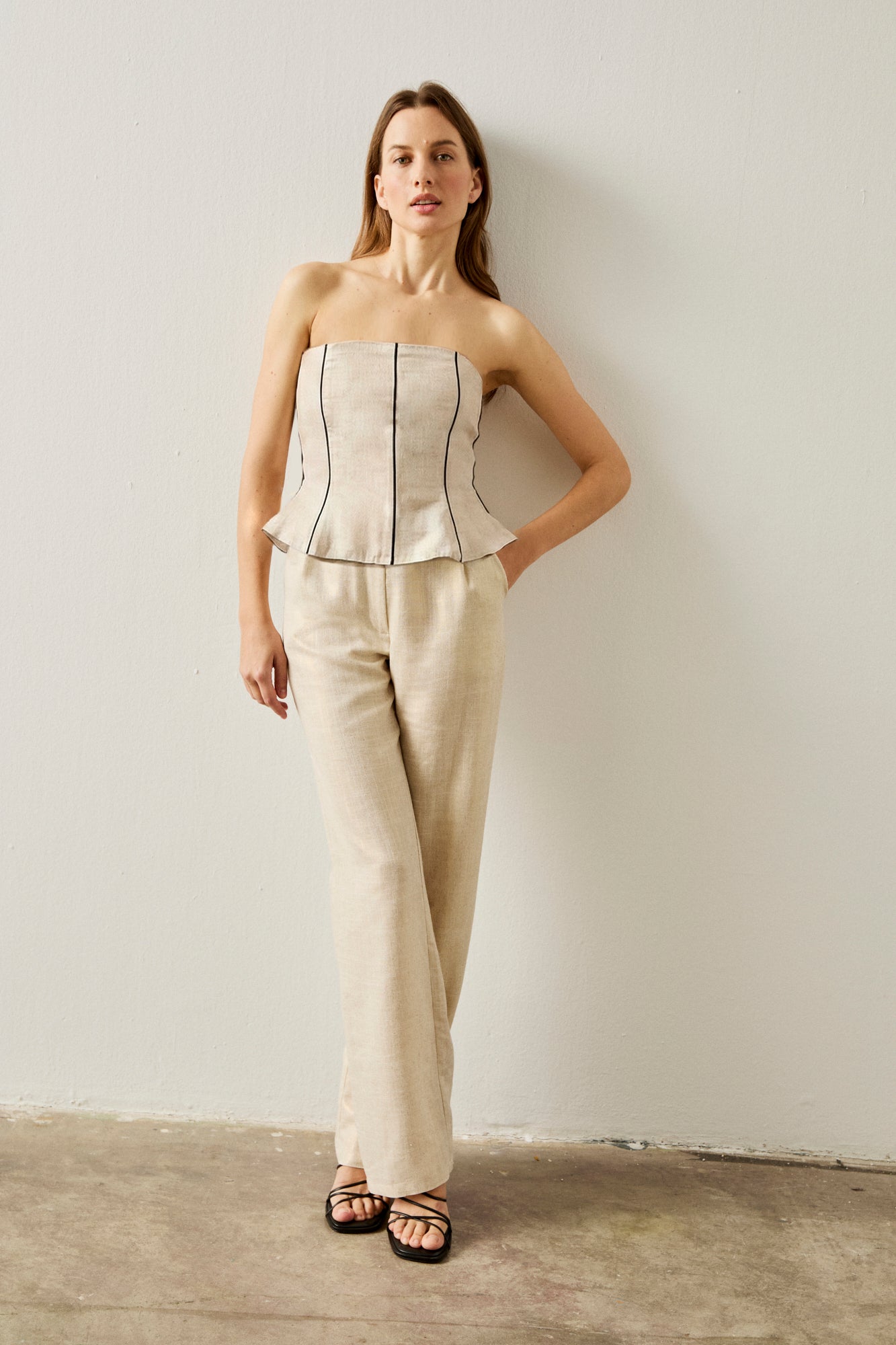 Pantalón de pinzas y pernera recta en color crema con ligero brillo.